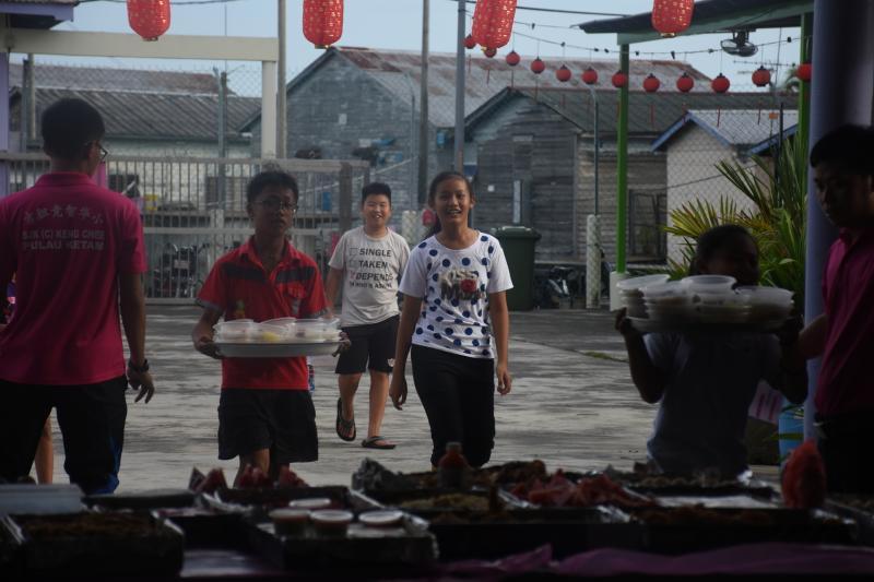 为学童准备中秋美食的父母兄姐,将食物送到校园,整齐陈列在礼堂外。