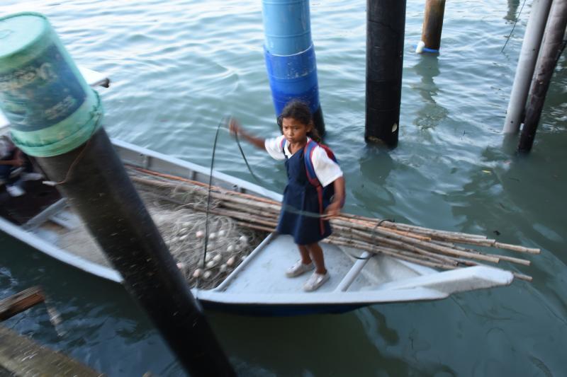 原住民小女孩在渔行渡头,协助父亲,为小舟系上绳索。