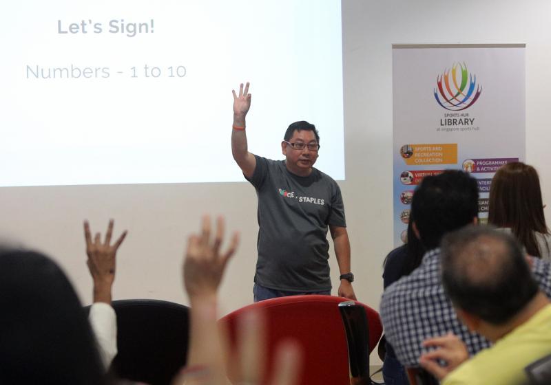 48岁的侍从协调员王为民在工作坊教导手语。