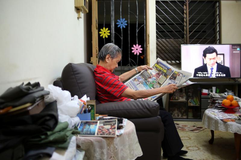 王钦祥的三房式组屋保留七八十年代典型的装潢,电视、神台、报纸供给他精神养分。