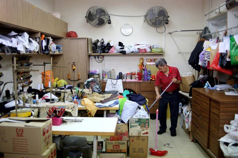 王钦祥赶完顾客的百褶裙才结束一天的辛劳,打扫裁缝店准备休息。