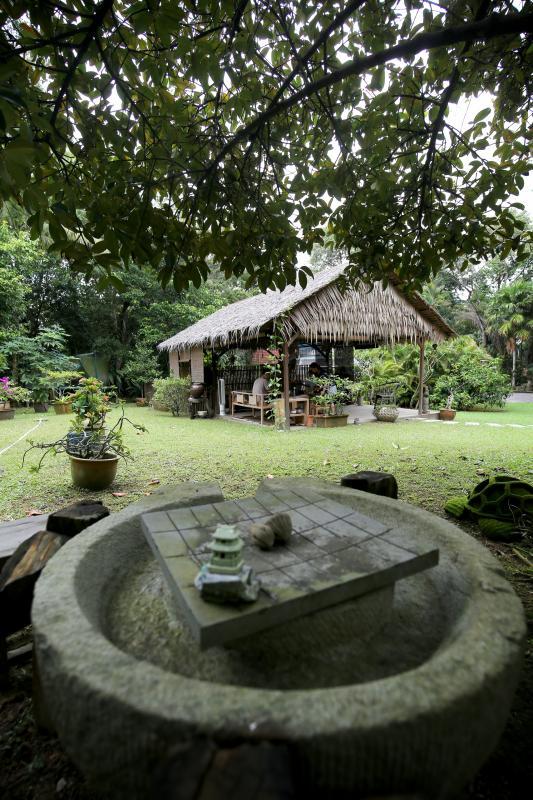 从石磨望出,主人家设计自筑亚答屋茶寮,成为住家的活动焦点。