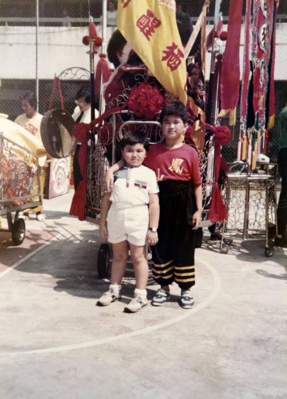 童年的陈志伟（右）和弟弟陈志铭在醒狮团前合照。（受访者提供）