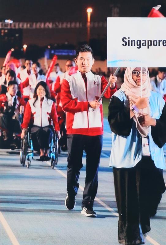 去年在迪拜举行的第三届亚洲青年残疾人运动会,黄智伟引领新加坡团队运动员步入会场。(受访者提供)