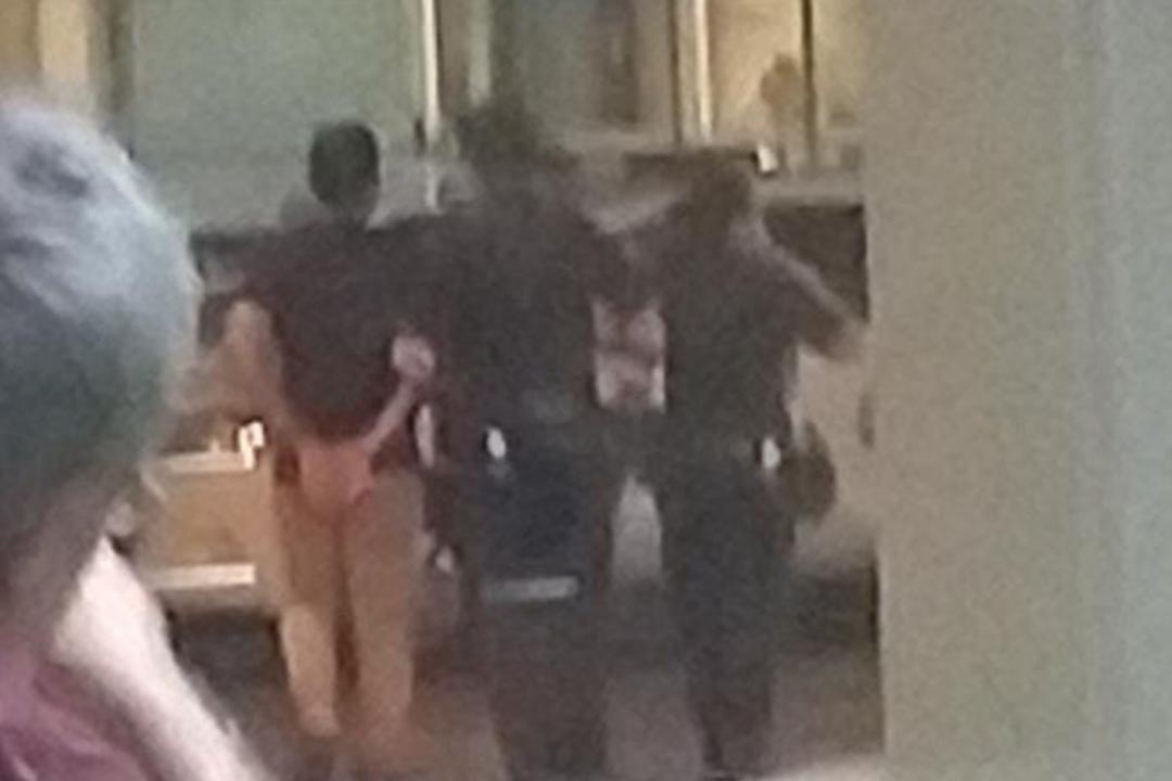 涉事的中年男子被警方上铐带走。（读者提供）