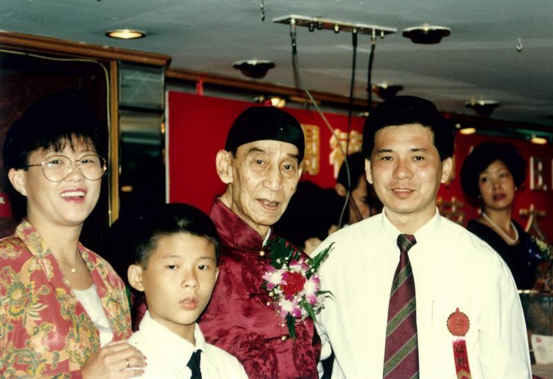 父亲陈军荣(右)带陈俊元(左二)看的第一部电影是《黄飞鸿》。曾参与该系列电影演出的关德兴(右二)庆祝87岁大寿时,一家人与他合影。(受访者提供)