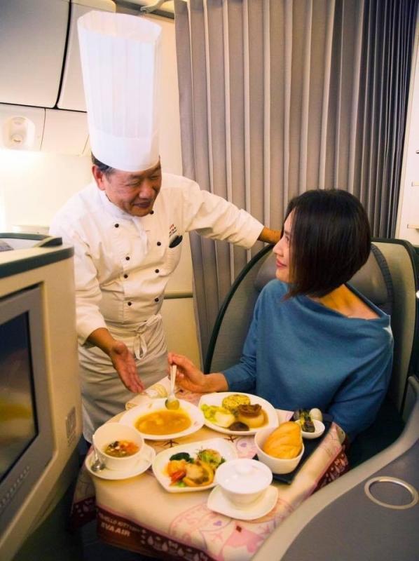 黄清标(左)在谭府官宴推出启航当日,在飞机上向乘客推介菜式。(长荣航空提供)