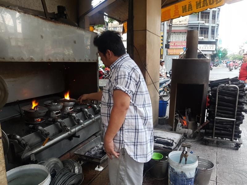 员工把材料满得快要溢出来的火锅,放到炭炉上加热。