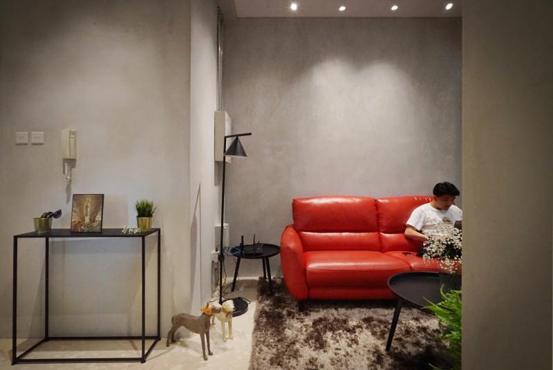 屋主要求客厅内一定要有一张红色沙发,设计师于是以粗犷的墙面和地毯搭配,制造不和谐但视觉冲击强烈的感觉。