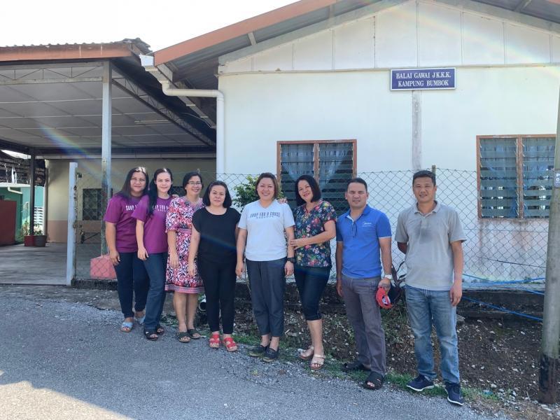 蓝慧敏(右四)与丈夫李家顺(右一)和蓬柏甘榜(Kampung Bumbok)的居民,他们身后的社区中心就是她想要设立肥皂工作室和社区厨房的地方。(陈映蓁摄)