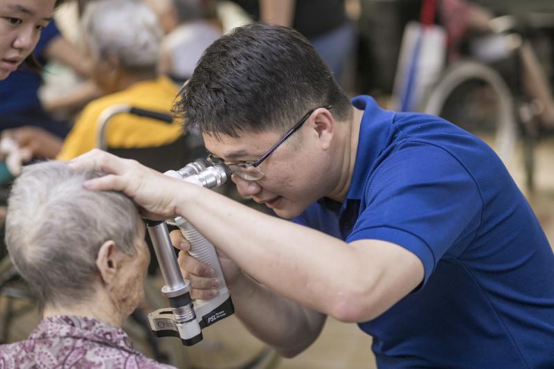 作为西北社理会社区委员，方齐扬医生经常到社区给年长者和贫穷者义务检查眼睛。（受访者提供）