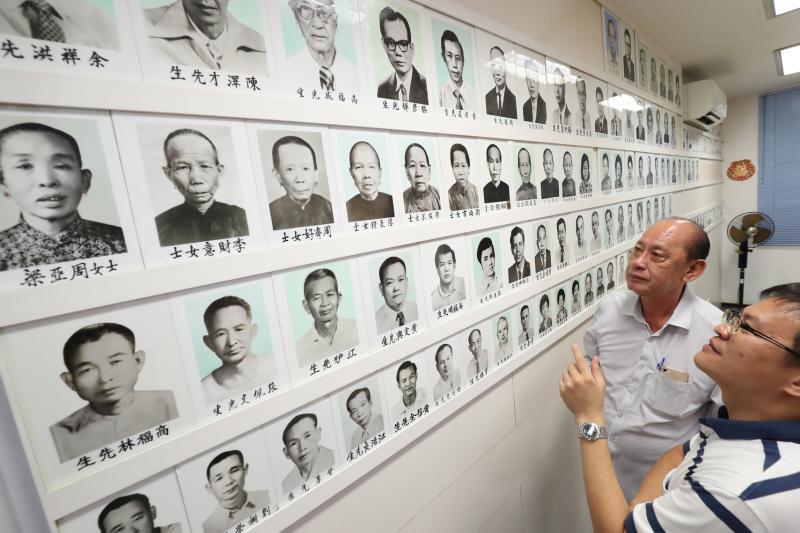 正会长曾锡源（左）和副会长庾潍诚发现，墙上老照片有不少是为花县会馆做出贡献的女会员，这在其他社团较少见。（陈来福摄）