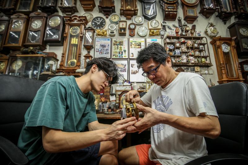 从中四开始学习修钟，林吉祥（左）大部分的童年都是与父亲林志光，在工作台前度过。 