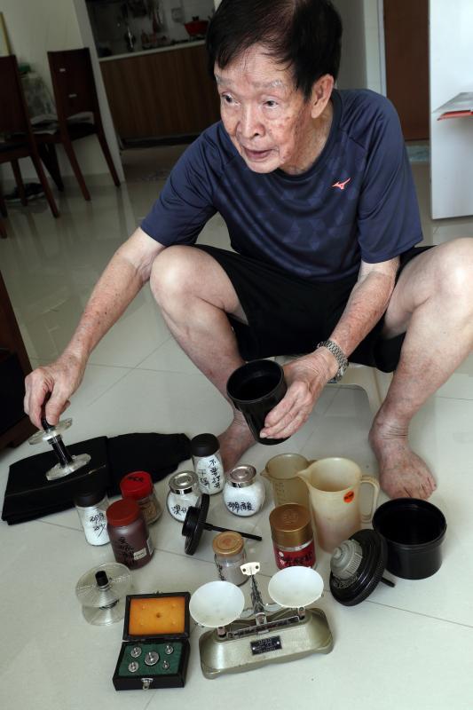 何国坚找出当年冲洗黑白照的旧器材和药粉,向记者讲解如何用手抄配方调配冲洗药剂。