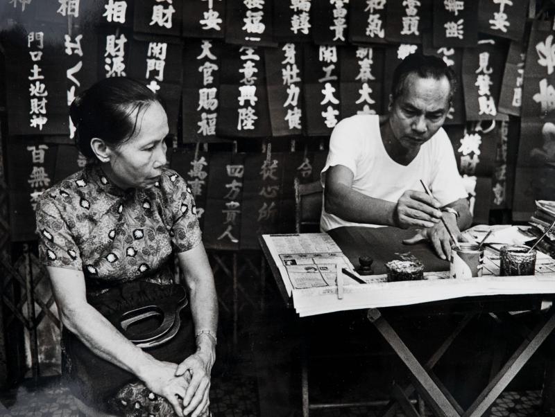 妙手挥春:六七十年代,写信佬越来越无用武之地,到了新年才有让他们发挥的机会。一张张红纸金字的挥春,写着普罗大众心中的愿望。摄影师留下悬念,让你猜猜这位妇人的新年愿望是什么?