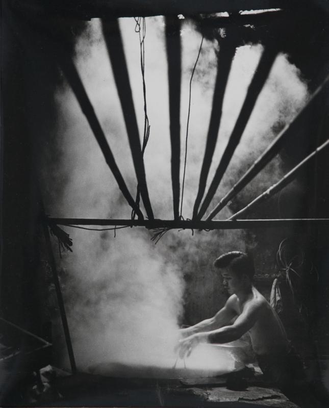 蒸河粉:1960年代,小坡汕头巷(位于今日甘榜格南)有家店屋专产粉类食品,供给本地酒楼、食铺。何国坚与供应商相熟,才能在1963年走入店里,近距离拍下这个镜头。师傅把粿条、河粉蒸好后,就一片片地挂上架子,待凉后切条。