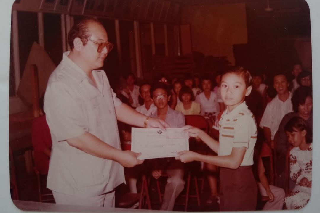 黄炯耀读小六时，从校董手中接获全校模范生奖状。（受访者提供）