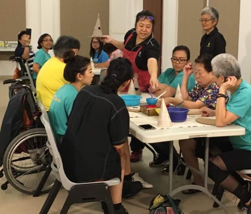 杨应愫(右四)与学生和好友教导残障人士做陶艺手工。