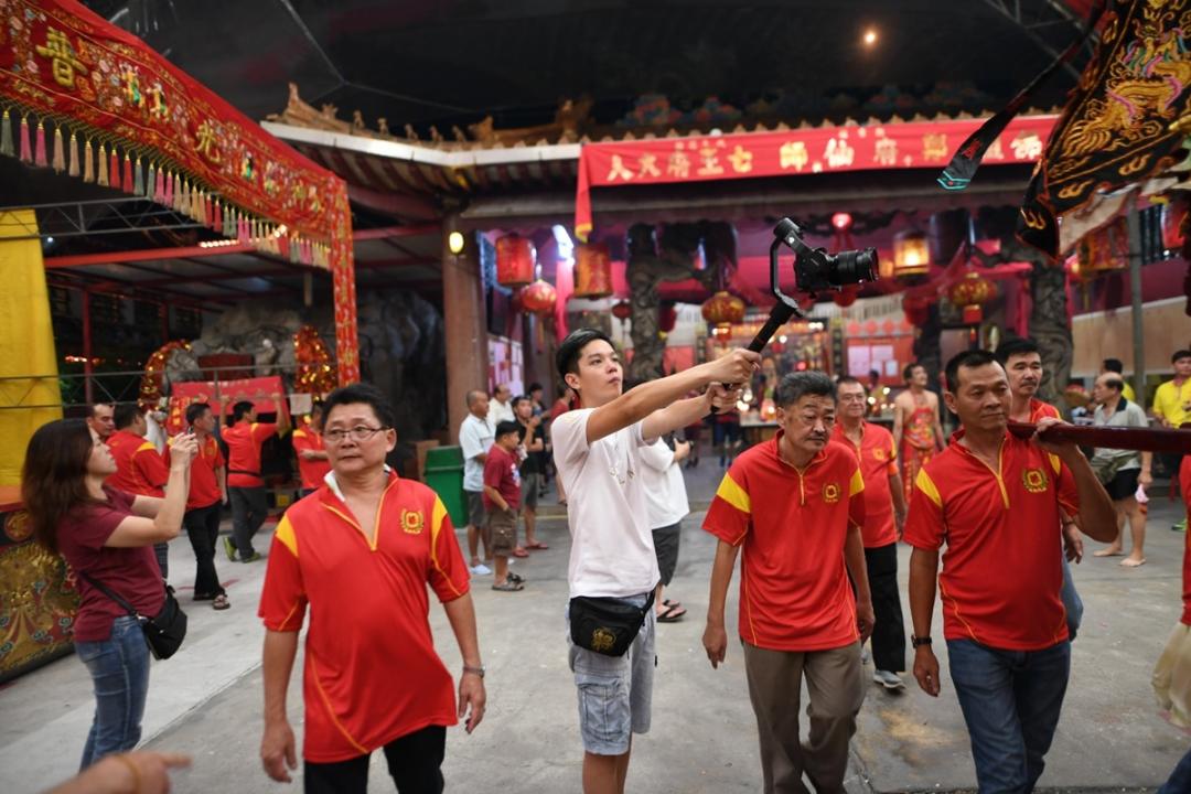 张瀚雄(白衣者)专心录下庙宇所办的绕境仪式,照片摄于阻断措施前。(受访者提供)