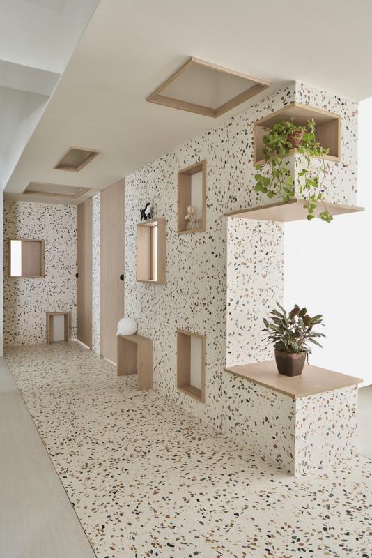 放在窗台上的小猫咪摆设让人将这水磨石伸展台联想成走猫步的T台。抬头望，方格还“攀”上天花板，变成了灯箱。  