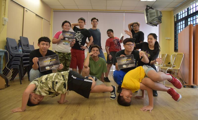 黄明凯（中间坐者）和一群街舞义工教导儿童掌握各种街舞技巧。（受访者提供）