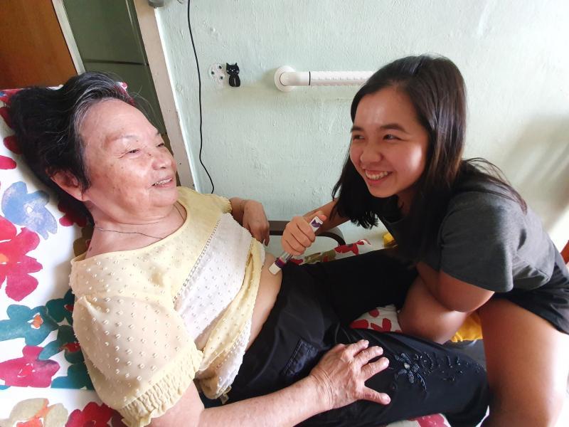 彭咏贤（右）替黄女德注射关节炎药物，她把黄女德当成“阿嫲”般关怀备至，给予对方充分的安全感。（林弘谕摄）