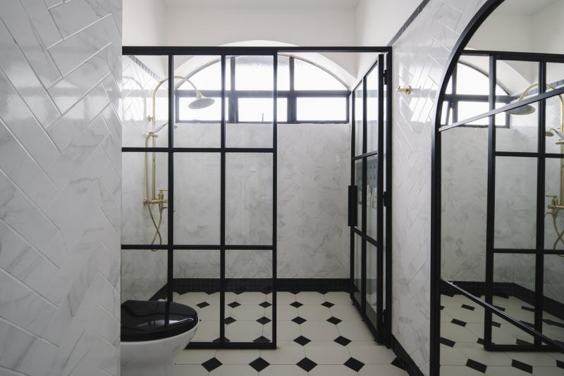 大门的黑铁框玻璃门设计语言延伸到浴室。设计师为主人找到一套金色的复古风花洒,让原本的复古风更上一层楼。