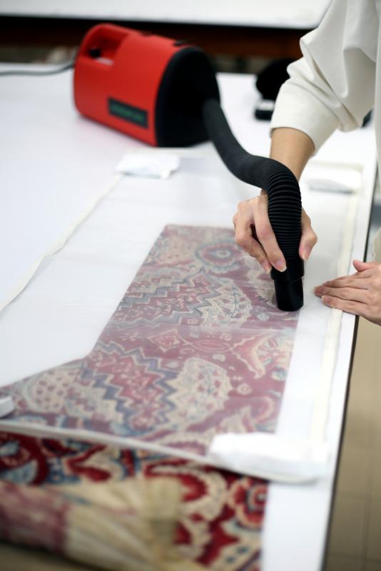 修复员以专用吸尘器小心翼翼地吸净纺织品表面的污尘。(龙国雄摄)