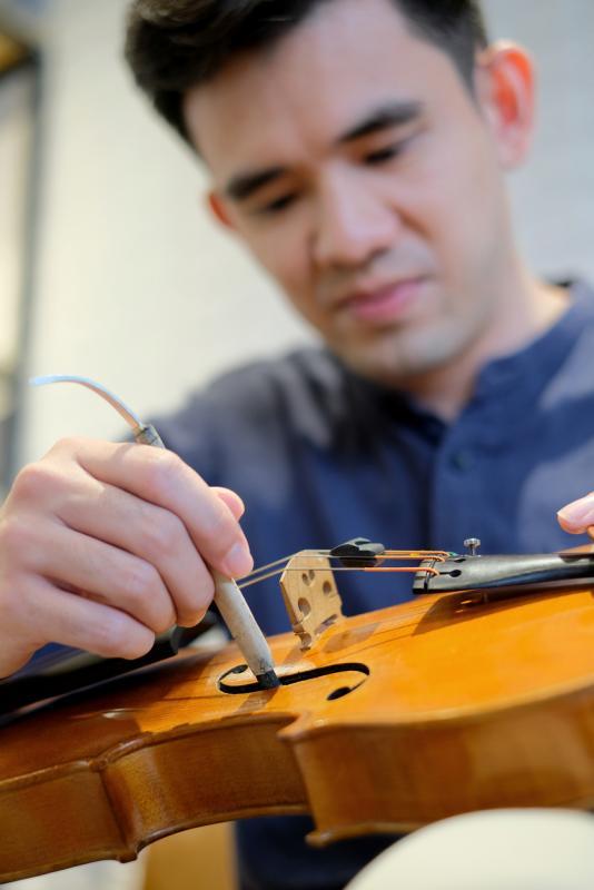 王韶军用特别的S钩,伸入小提琴里细心调整松脱的音柱。