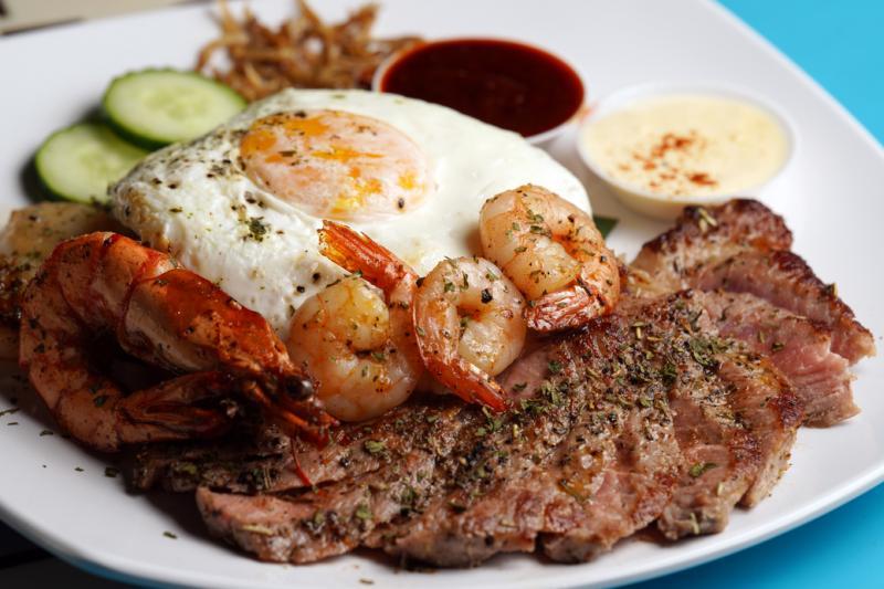 “西餐化”的椰浆饭里加入烤牛排、带子和虾子。(谢智扬摄)