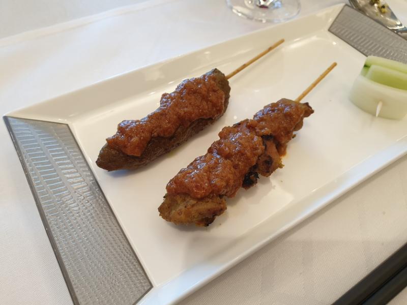 在媒体试吃活动上品尝新航招牌鸡肉沙爹(前)和植物肉沙爹。(黄亿敏摄)