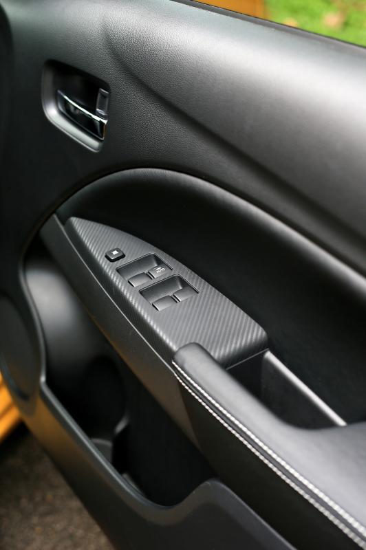 车侧类似碳纤维的塑料和皮革扶手，提升了质感。