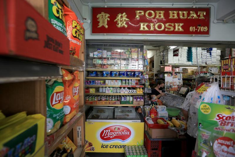 宝发杂货店常有邻里街坊光顾,老板娘卓甘叶忙里偷闲看报纸。