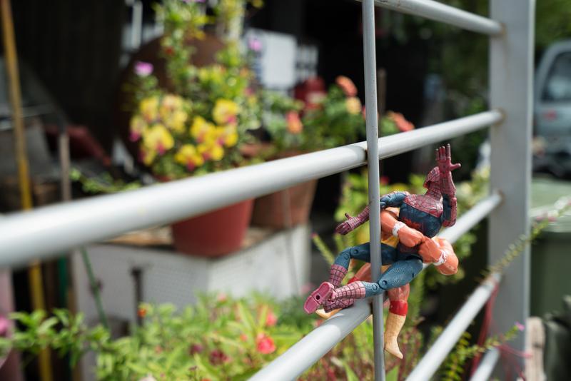 妇人把两个从路上捡到的超级英雄玩具挂在篱笆上。