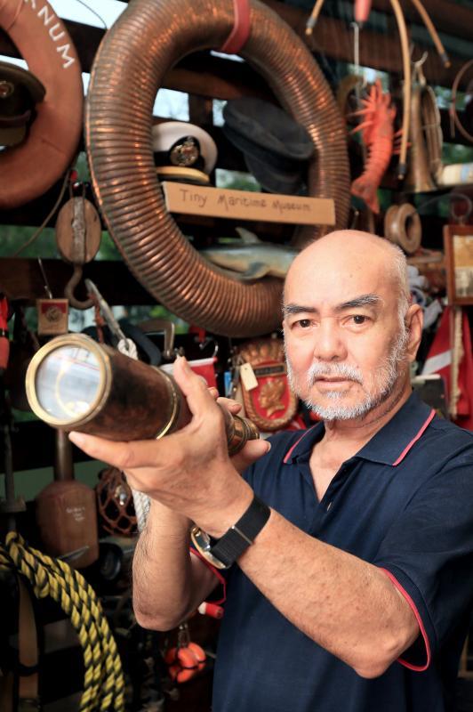 黄锦基在自己的古玩店里设了一个小小海事博物馆，麻雀虽小，五脏俱全。他透过收集了解航海微历史，他手上拿的是航海望远镜。（龙国雄摄）