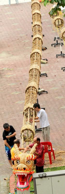 醒狮团兄弟在万山福德祠前的空地制作稻草火龙，场面壮观。（档案照）