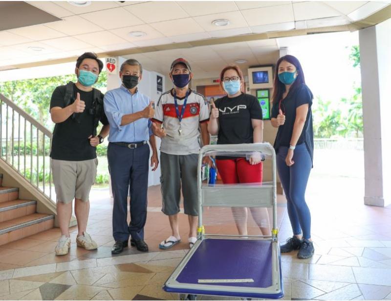 “Border Mission”发起人吴振华(左二)和义工把平板推车送给捡纸皮的年长者(中),让他工作起来较轻松。(Border Mission提供)