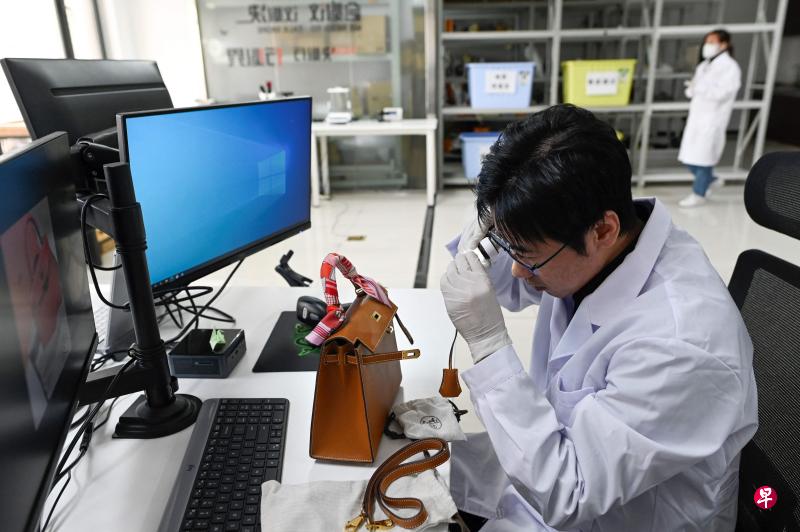 优奢商学院创始人张琛使用专业器材鉴定一个名牌包包。(法新社) 优奢商学院创始人张琛使用专业器材鉴定一个名牌包包。(法新社)
