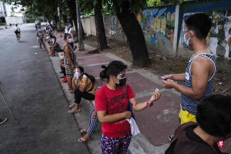 在马尼拉首都圈的奎松市,人们在街头排队领号,等候领取免费食物。冠病疫情导致菲律宾的失业者剧增,很多家庭再度跌落贫穷线下。(彭博社) 在马尼拉首都圈的奎松市,人们在街头排队领号,等候领取免费食物。冠病疫情导致菲律宾的失业者剧增,很多家庭再度跌落贫穷线下。(彭博社)