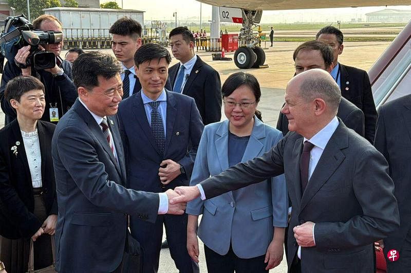 德国总理朔尔茨（右一）星期天飞抵重庆，与到场迎接的中国驻德国大使吴垦（左二）握手，重庆市副市长张国智（中）也在场迎接。（路透社）