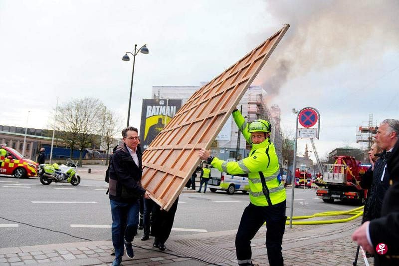 历史悠久的哥本哈根旧证券交易所4月16日发生火灾，紧急救援人员忙着抢救存放在这座历史大楼里的大型画作。（路透社）