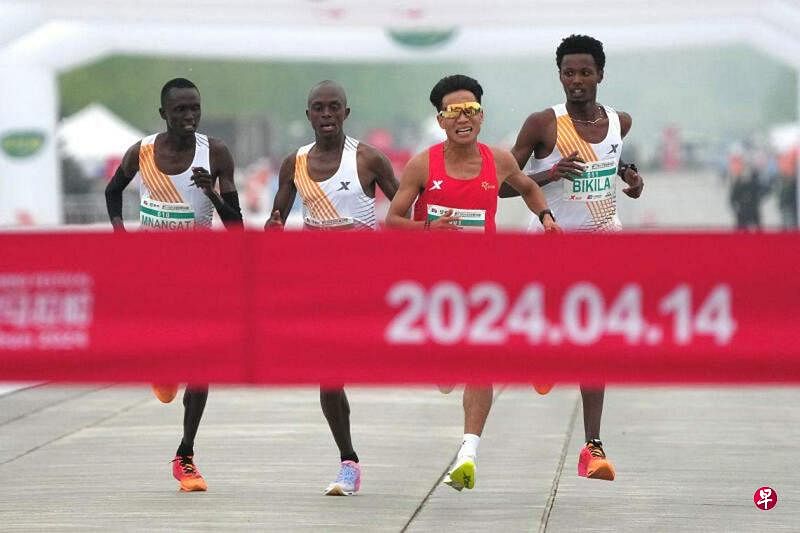 中国马拉松选手何杰（右二）与肯尼亚和埃塞俄比亚选手，几乎是并排接近北京半程马拉松赛的终点。（路透社）