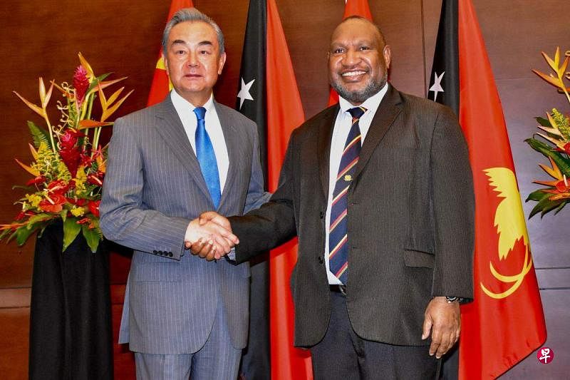 巴布亚新几内亚总理马拉佩（右）当地时间星期天（4月21日）在莫尔斯比港与到访的中国外交部长王毅（左）握手。（法新社）