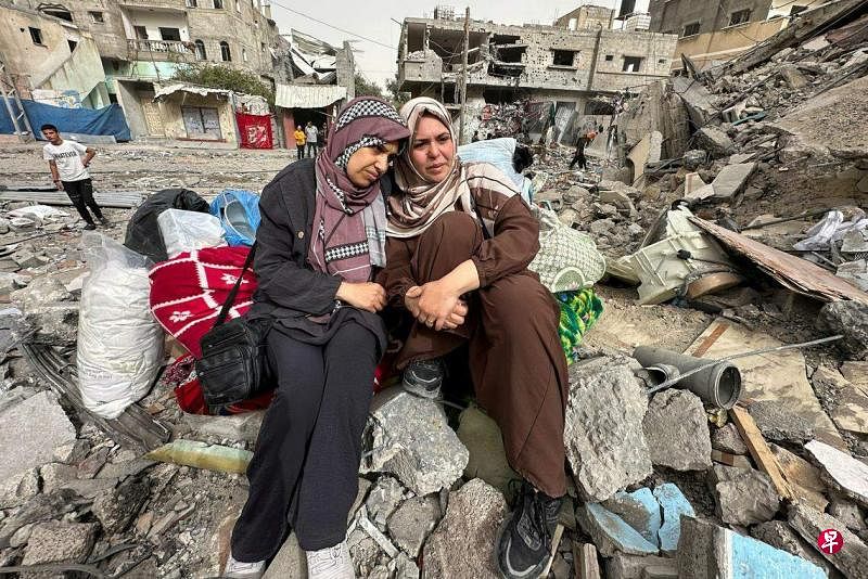 4月18日，加沙中部努塞拉特的巴勒斯坦居民坐在一座住宅楼的废墟上。（路透社）