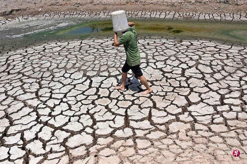 3月19日，一名男子穿过越南南部槟椥省干涸池塘的破裂河床。由于炎热天气将提振电力消耗，越南政府敦促煤矿企业增加产量。（法新社）