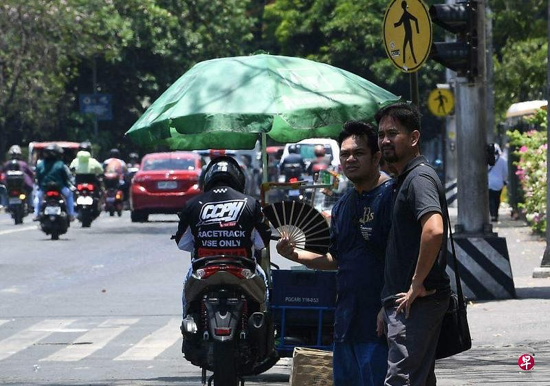 4月24日，热浪席卷菲律宾，马尼拉市民在街上打伞遮阳。（法新社）