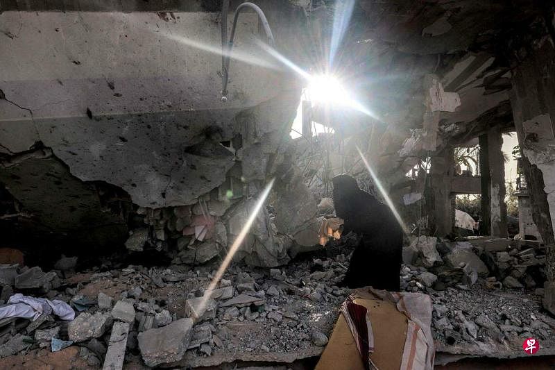 4月24日，一名女子在加沙地带南部拉法一座遭以军袭击后倒塌的楼房的废墟上寻找。（法新社）