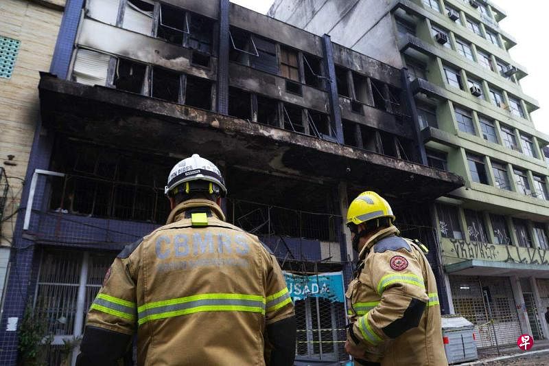 4月26日，消防人员在阿雷格里港市的火灾现场开展工作。这座三层建筑已经严重烧毁。（法新社）