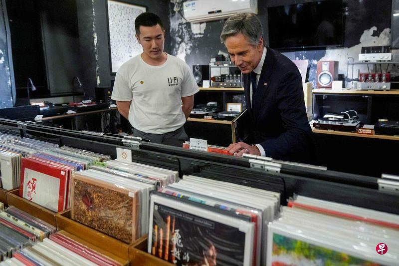 美国国务卿布林肯（右）星期五（4月26日）在离开中国前，到访位于北京798艺术区的一家黑胶唱片行。图为布林肯和唱片行店主交谈。（法新社）