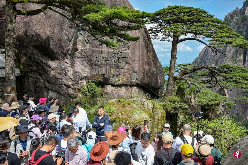 大批游客星期六（4月27日）在中国安徽黄山风景区迎客松前游览拍照，“五一”黄金周假期未至，该景区已经提前迎客。（中新社）